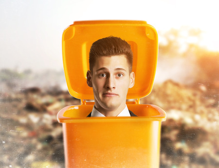 Pensive businessman standing inside a trash can isolated on white backgroundの写真素材
