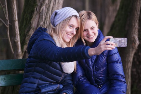 Young woman sitting on bench with her best friend.の写真素材