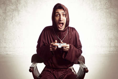 young friar playing with console joystick on grunge backgroundの写真素材