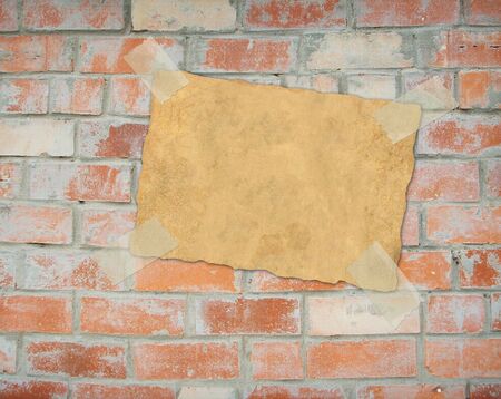 Sheet of old a paper, hanging on a brick wallの写真素材
