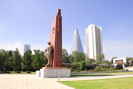 NORTH KOREA, PYONGYANG - SEPTEMBER 20, 2017: Museum of Victory. Statue of a soldier with a flag at the entrance to the Victorious Fatherland Liberation War Museum and Ryugyong Hotel. North Korea (DPRK)のeditorial素材