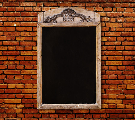 Wooden sign with blank black menu board with floral ornament, drawn in chalk on old brick wallの写真素材