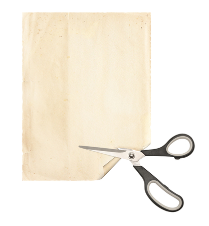 Scissors with dark gray handles cut a sheet of old paper. Objects isolated on white background. Copy space for text. Mock up templateの写真素材