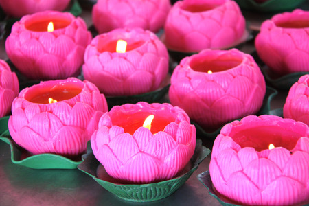 Burning candles in glass candlesticks in the form of a lotus of magenta color, buddhist temple, Penang island, Malaysiaの写真素材