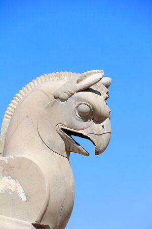 Fragment of stone column sculpture of a two-headed griffin in the ancient city of Persepolis, Iran. UNESCO World heritage site. On blue sky backgroundの写真素材