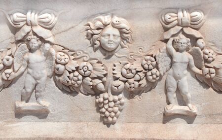 Carved ornament with cupids and a flower garland on a stone sarcophagus, ancient Hierapolis, Pamukkale, Turkey.の写真素材
