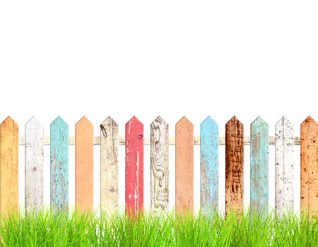 Rustic wooden fence and green grass. Old fence with vintage boards with cracked paint of red, white, brown, orange and blue color. Isolated on white background. 3d renderの写真素材