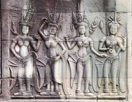 Wall carving with four womans dancers apsara, famous Angkor Wat complex, Siem Reap, Cambodia. Horizontal background with stone texture and bas-relief with dancing girls.の写真素材