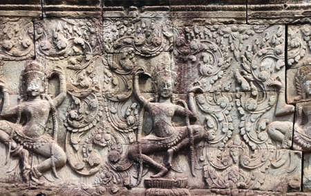 Wall carving with two womans dancers apsara, famous Angkor Wat complex, Siem Reap, Cambodia. Horizontal background with stone texture and bas-relief with dancing girlsの写真素材
