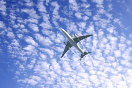 Vertical nature background with aircraft and Jet trailing smoke in the sky. Airplane and condensation trail. Foggy trail jet and plane in blue sky with white clouds. Traveling the world conceptの写真素材