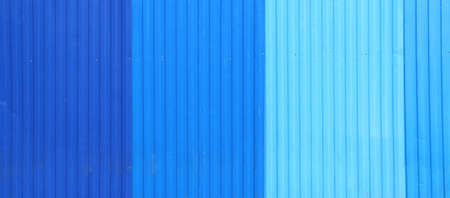 Wave Sheets fence of dark blue, blue and cyan colors. Horizontal background with galvanized iron sheets of different shades of blue color. Colored corrugated metal roofing sheetの写真素材