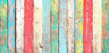 Texture of vintage wood boards with cracked paint of white, red, orange, yellow, cyan and blue color. Horizontal retro background with old wooden planks of different colorsの写真素材