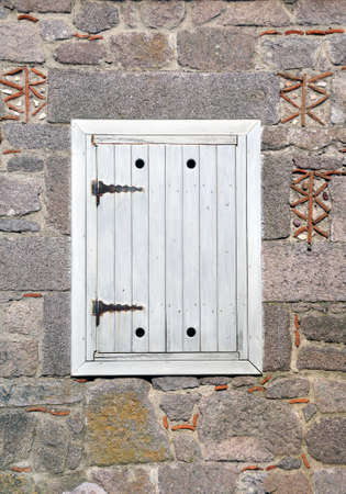 Antique painted wooden shutter. Closed window shutter on the wall of old stone houseの写真素材