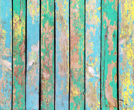 Texture of vintage wood boards with cracked paint of yellow, green, cyan and blue color. Horizontal retro background with old wooden planks of different colorsの写真素材