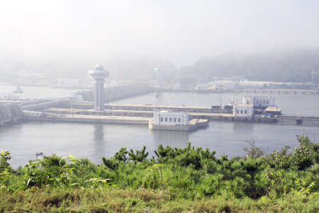 The Nampho Dam (West Sea Barrage) on the river Tedongan, Nampho, North Korea (DPRK). Korean hydroelectric power station West Sea Dam in the morning mistの写真素材