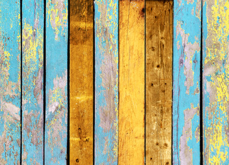 Texture of vintage wood boards with cracked paint of yellow and blue color. Horizontal retro background with old wooden planks of different colorsの写真素材