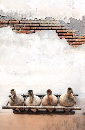 Vertical banner with Old pitchers on white stucco wall. Vintage clay wine jars on concrete wall. Traditional mediterranean wall decoration of a village house. Mock up template. Copy space for textの写真素材