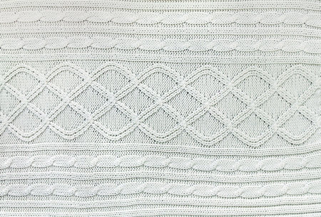 Wool sweater texture of white color with cable knitting stitch pattern. Natural knitted wool white material with ornament. Horizontal or vertical background with handmade knitted fabric textureの写真素材