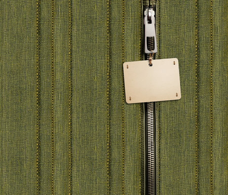 Dark green denim background with zipper and paper tag. Khaki color denim jeans fabric texture, close zip and cardboard label. Mock up template. Copy space for textの写真素材