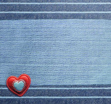 Blue denim background with striped borders and red felt heart. Navy color denim jeans fabric texture. Valentine's day denim backdrop. Copy space for textの写真素材