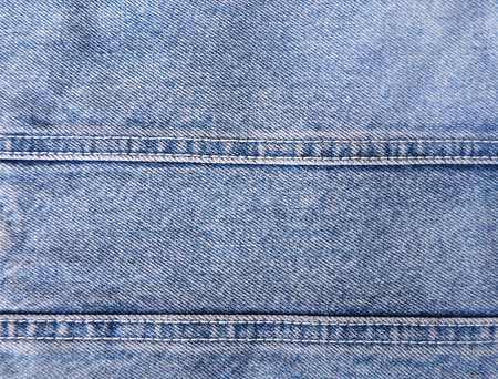 Blue denim background with a seam. Light blue color denim jeans fabric texture. Copy space for textの写真素材