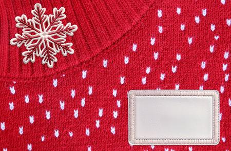 Horizontal Christmas background with knitted fabric texture, felt snowflake and leather tag. Wool sweater texture of red color with white dotted. Mock up template. Copy space for textの写真素材