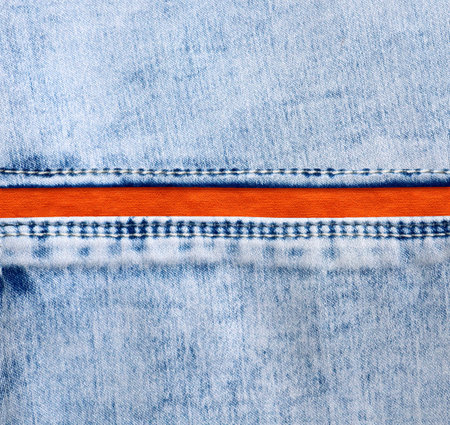 Blue denim borders with a seam and orange cotton texture. Light blue and orange color denim jeans fabric. Copy space for textの写真素材