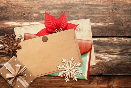 Christmas background with retro card, vintage envelope, poinsettia, gift and wooden snowflakes on old wooden boards. Nostalgic scrapbooking backdrop. Mock up template. Copy space for textの写真素材