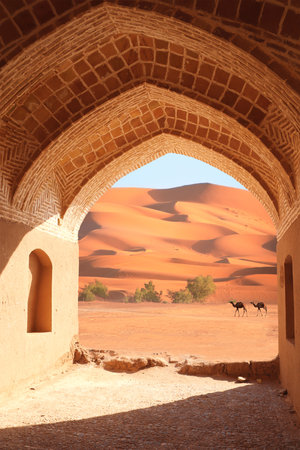 Ancient arch at the entrance to desert. View of sand dunes through stone arch. Travel, resort, vacation and holiday concept. Beautiful desert landscape with sand dunes and camelsの写真素材