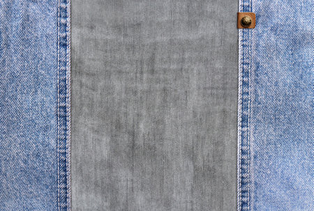 Horizontal background with blue denim borders with a seam, leather label and light grey cotton texture. Decorative backdrop with light blue and gray color denim jeans fabric. Copy space for textの写真素材