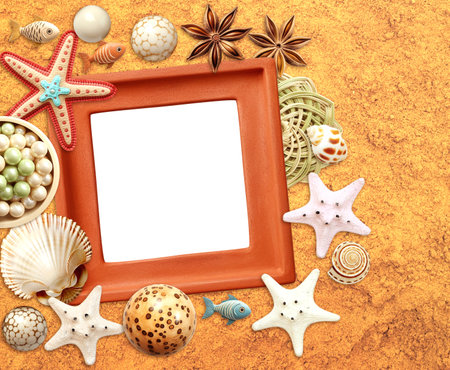 Vintage travel background with clay frame, vacation souvenirs, small wooden fish, seashell on sand. Horizontal summer holiday backdrop. Mock up template. Copy space for textの写真素材