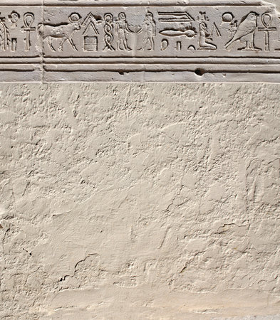 Vertical background with ancient Egyptian hieroglyphs on stone wall, Egypt, Africa. Backdrop with sandstone carving with hieroglyph. Mock up template. Copy space for textの写真素材