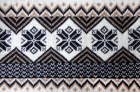 Wool sweater texture with decorative ornament of white, black, light brown and beige color. Natural wool material with knitted ornament. Horizontal or vertical background with knitted fabric textureの写真素材