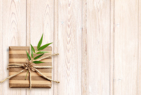 Horizontal eco backdrop. Craft paper wrapped gift with green leaf on old wooden boards. Ecology, environmental conservation and zero waste concept. Mock up template. Copy space for textの写真素材