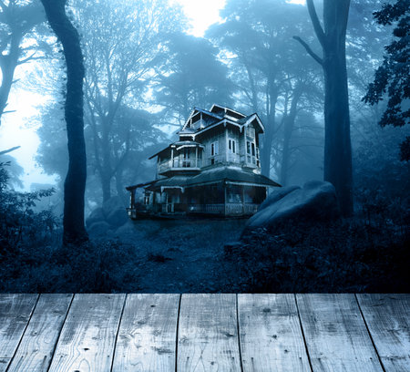 Halloween banner with haunted house and blank wooden table top. Wood terrace flooring and abandoned house in night forest. Scary colonial cottage in mysterious forestland. Photo toned in blue colorの写真素材