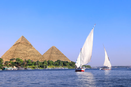 Famous Great Pyramids of Chephren and Cheops and traditional sailing boat felucca, Nile river, Egypt. A famous tourist attraction - sailing boat rideの写真素材