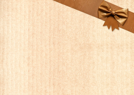Paper package covered in adhesive tape with decorative bow. Masking tape with paper. Vintage grunge adhesive tape strips and bow on old cardboard texture of brown color. Copy space for textの写真素材
