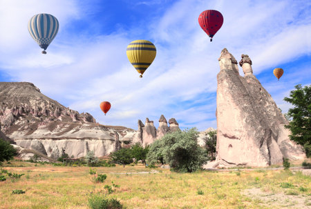 The balloon flight, famous tourist attraction of Cappadocia. Air balloons and Fairy Chimney (multihead stone mushrooms) in Pasabag Valley, Cappadocia, Anatolia, Turkeyの写真素材