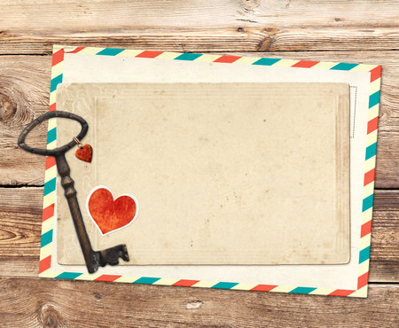 Cute Valentine background with key with a heart pendant, retro postcard on wood board. Backdrop with vintage key, old card on wooden plank. Nostalgic scrapbooking mock up template. Copy space for textの写真素材