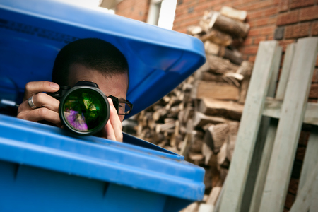 Paparazzi hiding in a blue garbage bin to take pictures