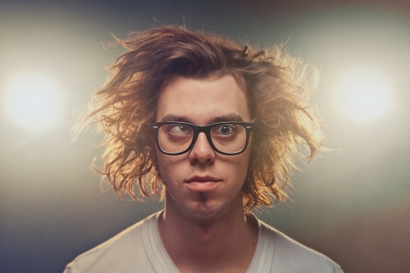 Funny Squinting man with Tousled brown hair in studio using spotlights in background