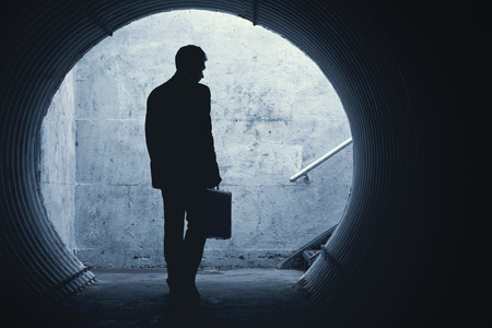 Businessman in Silhouette Walking in a dark tunnel. With room for your Textの写真素材
