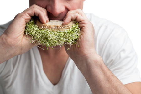 Young Adult Eating a Sandwich Full of Alfalfa Sprouts (healthy lifestyle concept)
