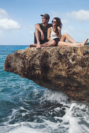 Beautiful Couple sitting on a rock and Looking at The View in San Andres Island, Colombiaの写真素材