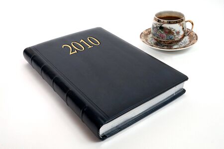 New diary of 2010 and beautiful cup of coffee. Isolated on white