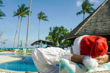 Man in Santa Claus Hat Relaxes by the Pool shot with a Sony a6300の写真素材