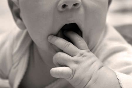 The image of a part of the face of the child a hand in a mouth. B/W+sepiaの写真素材