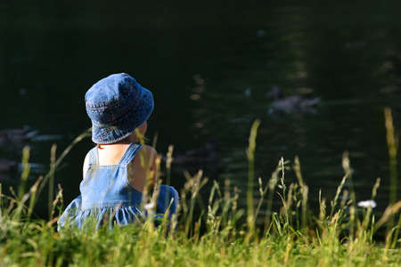 The girl sits on a coast of lakeの写真素材