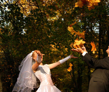Wedding fun. he groom and the bride throw upwards leavesの写真素材