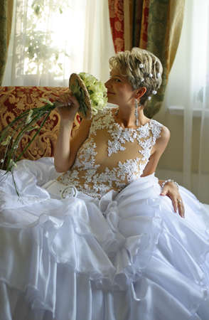 The beautiful bride with a bouquet in an interiorの写真素材